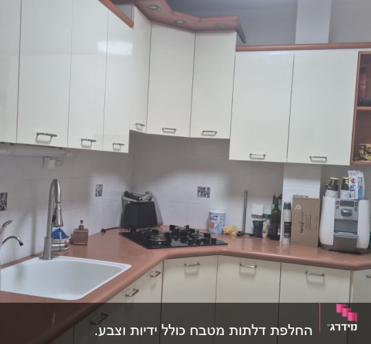 מטבח עם ארונות לבנים, כיור וברז, כיריים ותנור